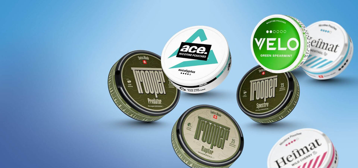 Snus és nikotintasak választék: Nоoper, Velo Green Spearmint és Heimat dobozok kék háttéren