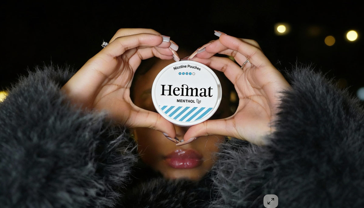 Heimat Menthol Nikotin Pouches Adag szív alakban tartva, lifestyle fotó egy fekete kabátban lévő nővel